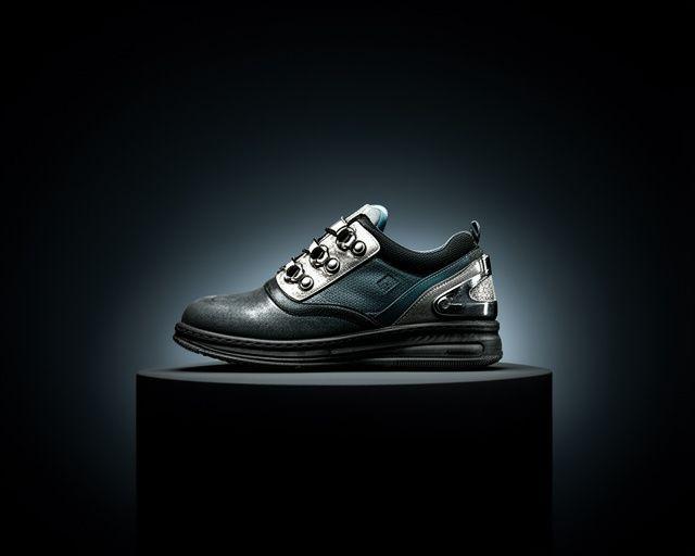 Urban shoe with metallic accents displayed on a dark studio pedestal with clean side lighting